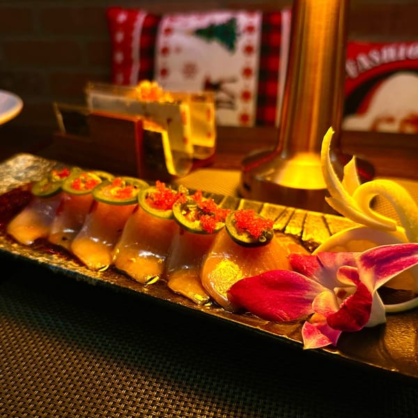 Yamashiro's sushi dish with jalapeños, red roe, and an orchid on a dark plate.
