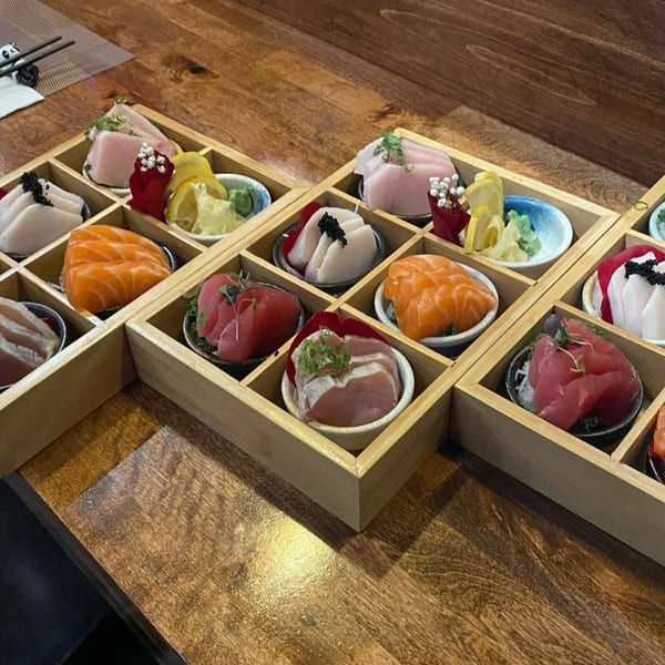 A wooden tray filled with various types of sashimi, including tuna, salmon, and yellowtail.